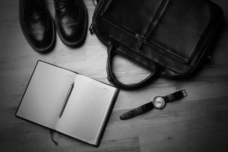 business shoes, watch, laptop case and open notebook on a floor