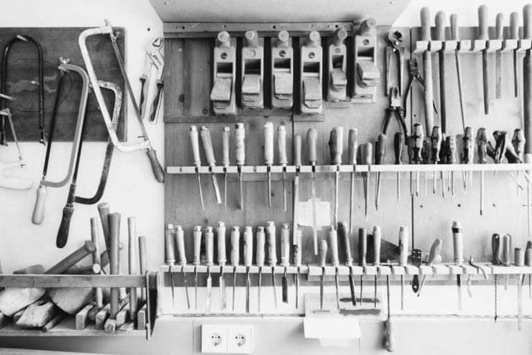 neatly organized carpenter tools on a wall of a carpenter shop