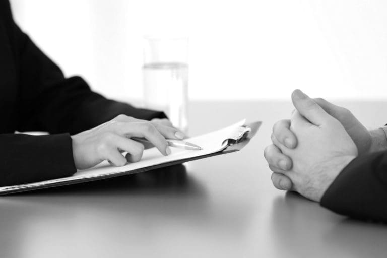 An interviewer holding a resume sitting in front of an applicant
