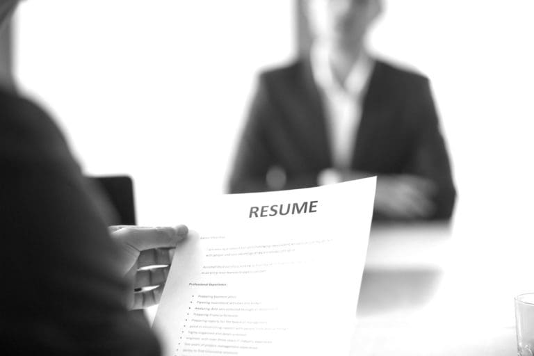 An interviewer holding a resume sitting in front of an applicant