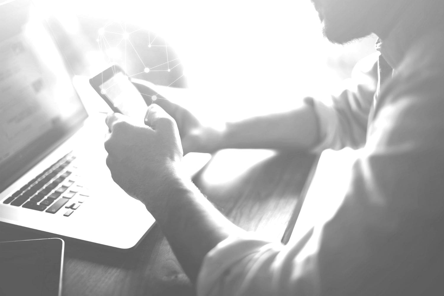 Person working on a smartphone while sitting in front of a laptop