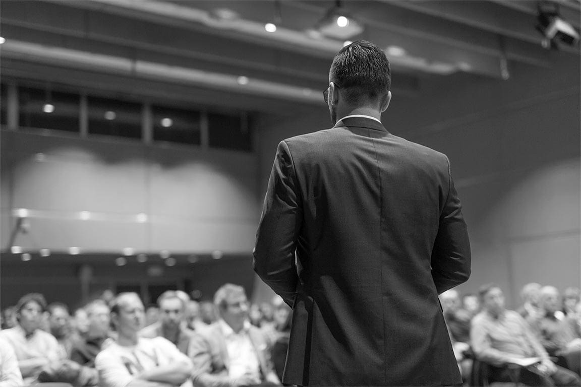 Person presenting to a large group of people at a conference