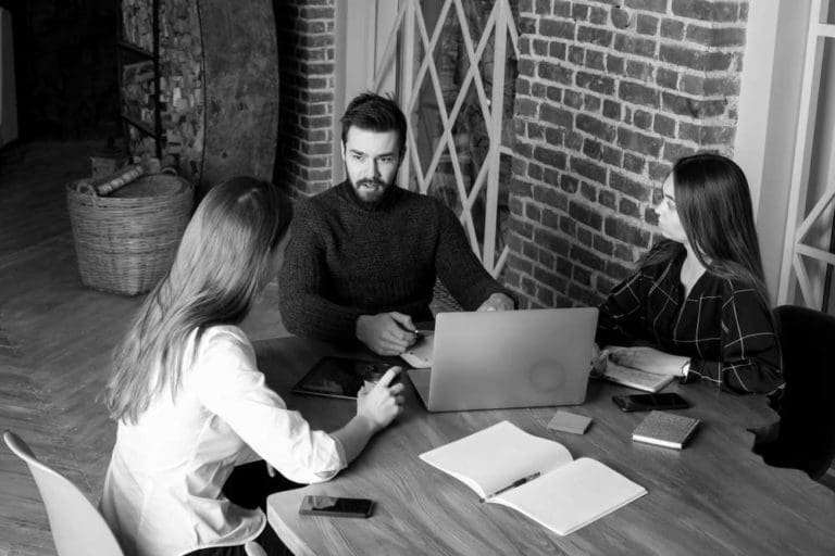 Young professionals in an office setting collaborating while looking at a computer screen